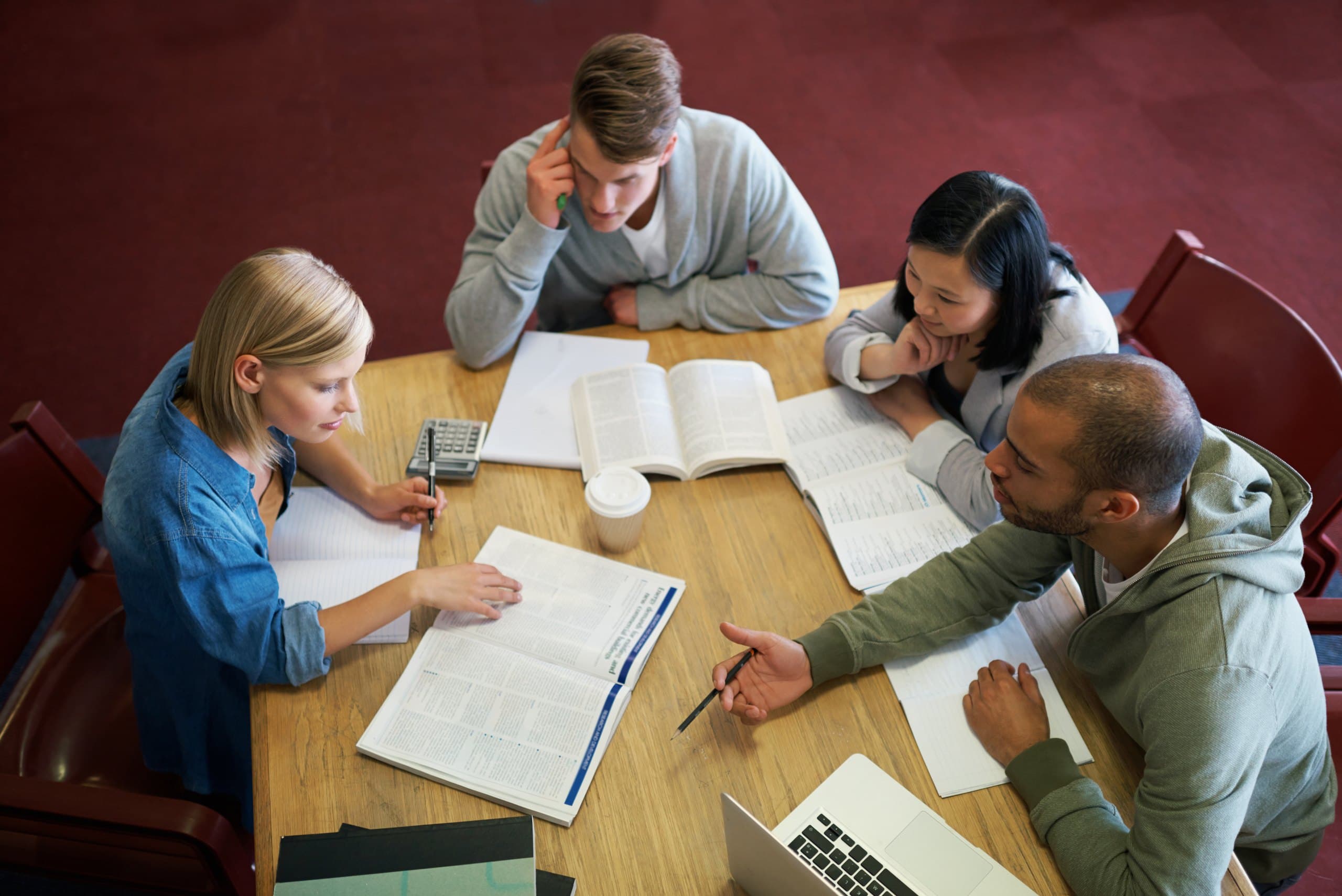 Four students studying together around a table of books