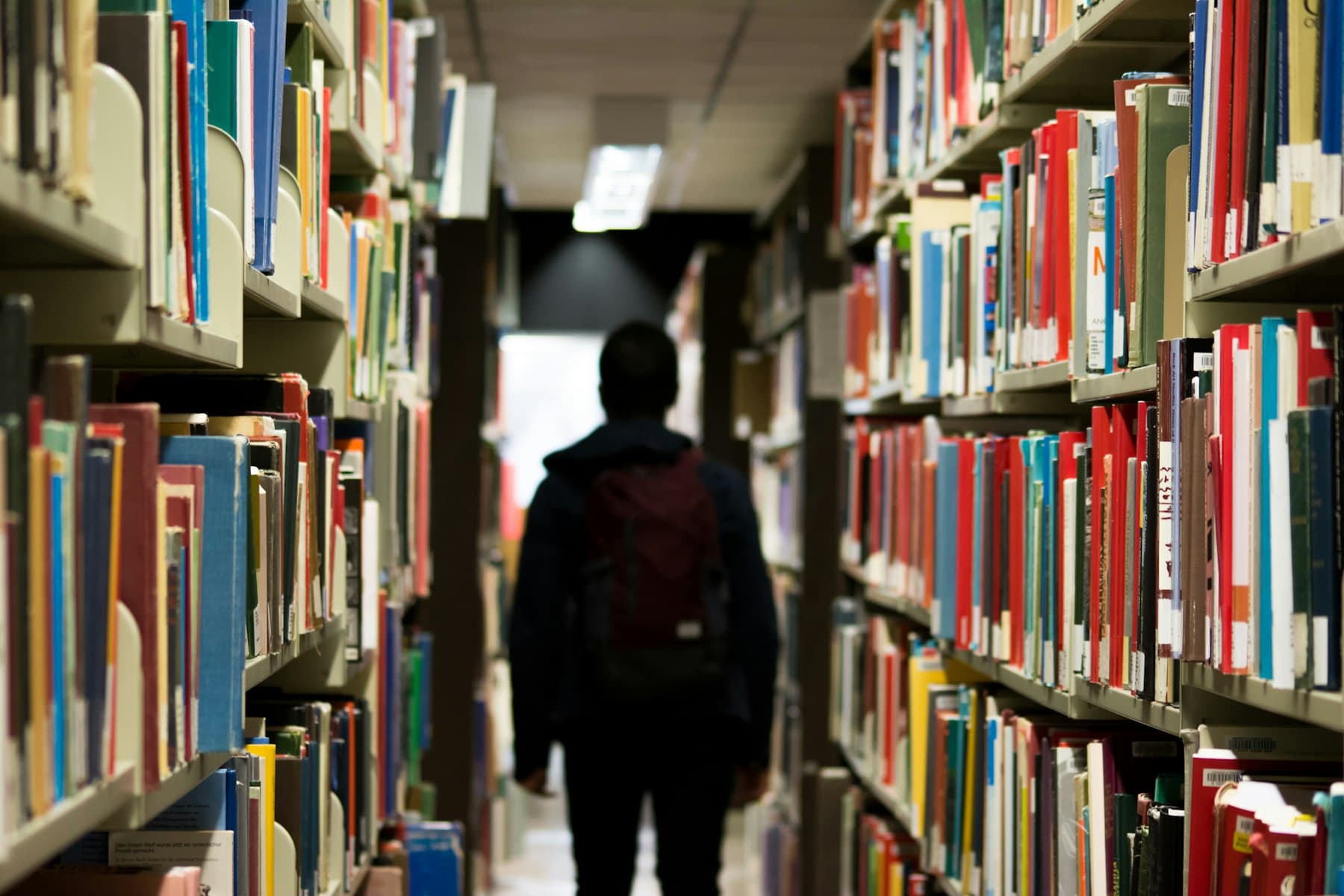 Student walking between library shelves